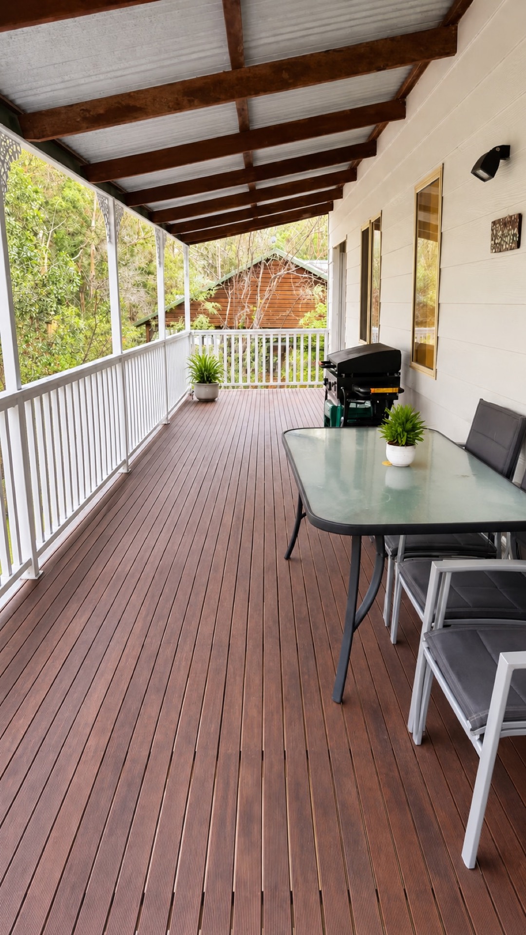 Long timber balcony with white railing and dining area